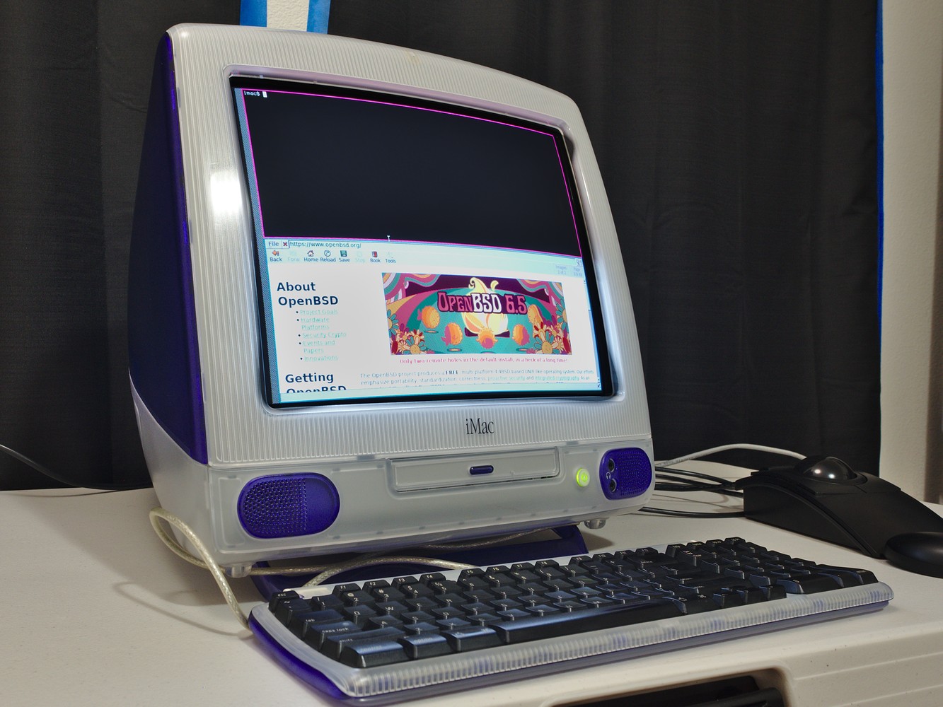 iMac G3 on a desk; screen shows the
minimalist cwm window manager and single dillo browser window.